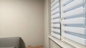 Ein Eckzimmer mit grauem Sofa, einem kleinen Holztisch und einer Heizung.