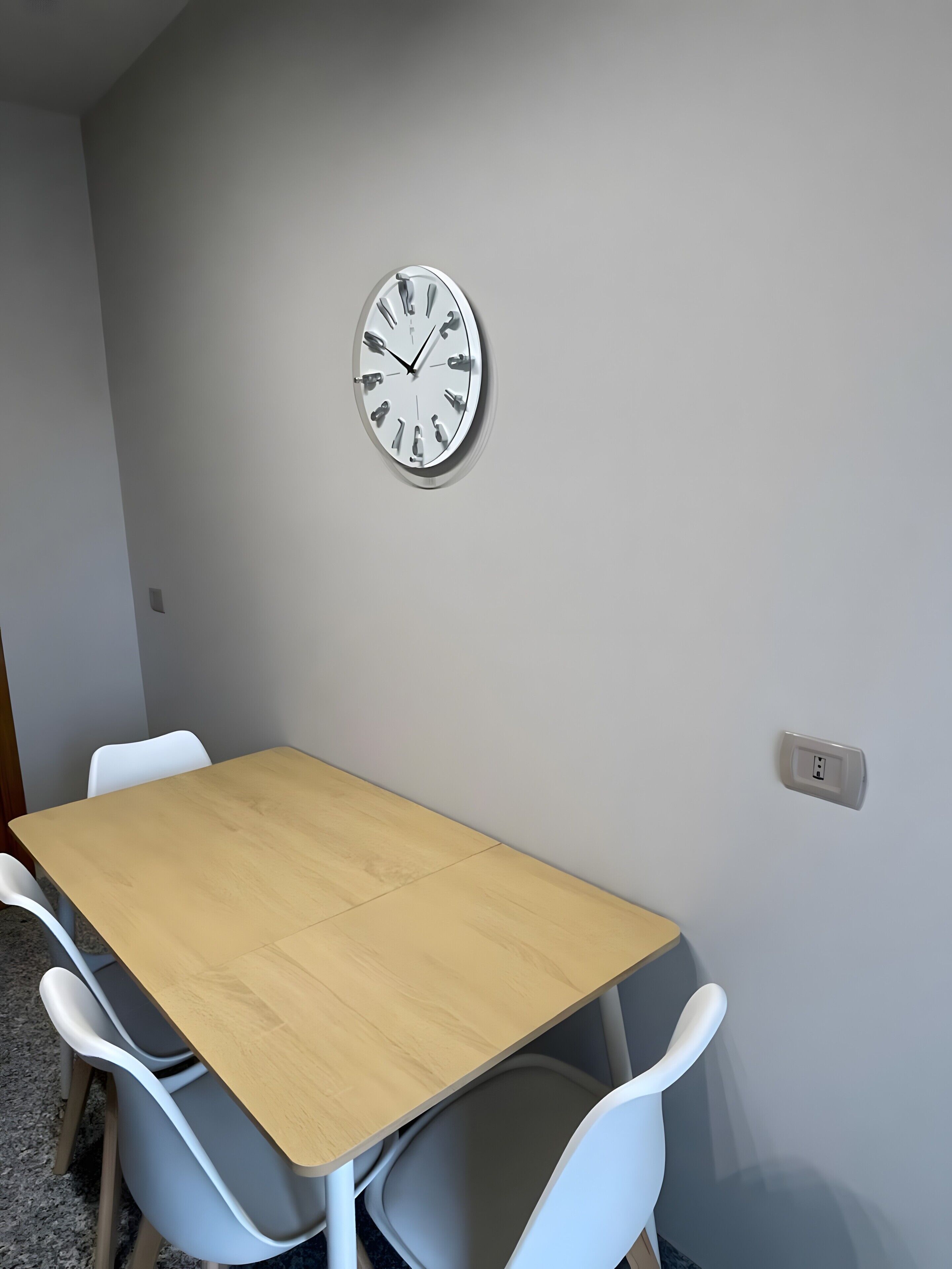 A conference room with a wooden table, white chairs, and a wall clock.