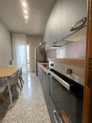 A modern kitchen with stainless steel appliances, a wooden countertop, and a dining area with a table and chairs.