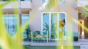 Un edificio moderno con grandes ventanales, un patio con mobiliario exterior y un césped bien cuidado.