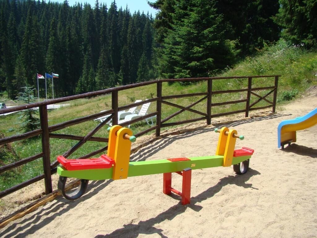 A seesaw with a metal fence in the background.