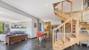 Un vaste espace de vie comprenant un escalier en bois, une table à manger et un canapé.