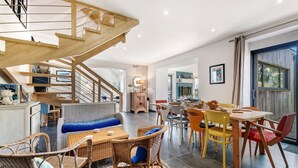 Un vaste espace de vie comprenant un escalier en bois, une table à manger avec des chaises et un canapé.