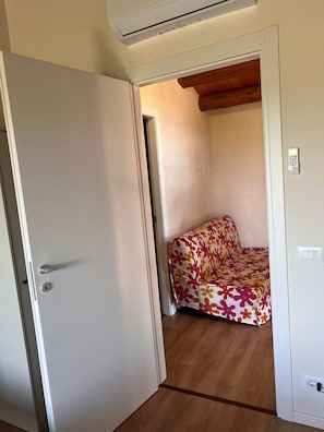 Una habitación con una cama, aire acondicionado, una puerta y techo de madera.