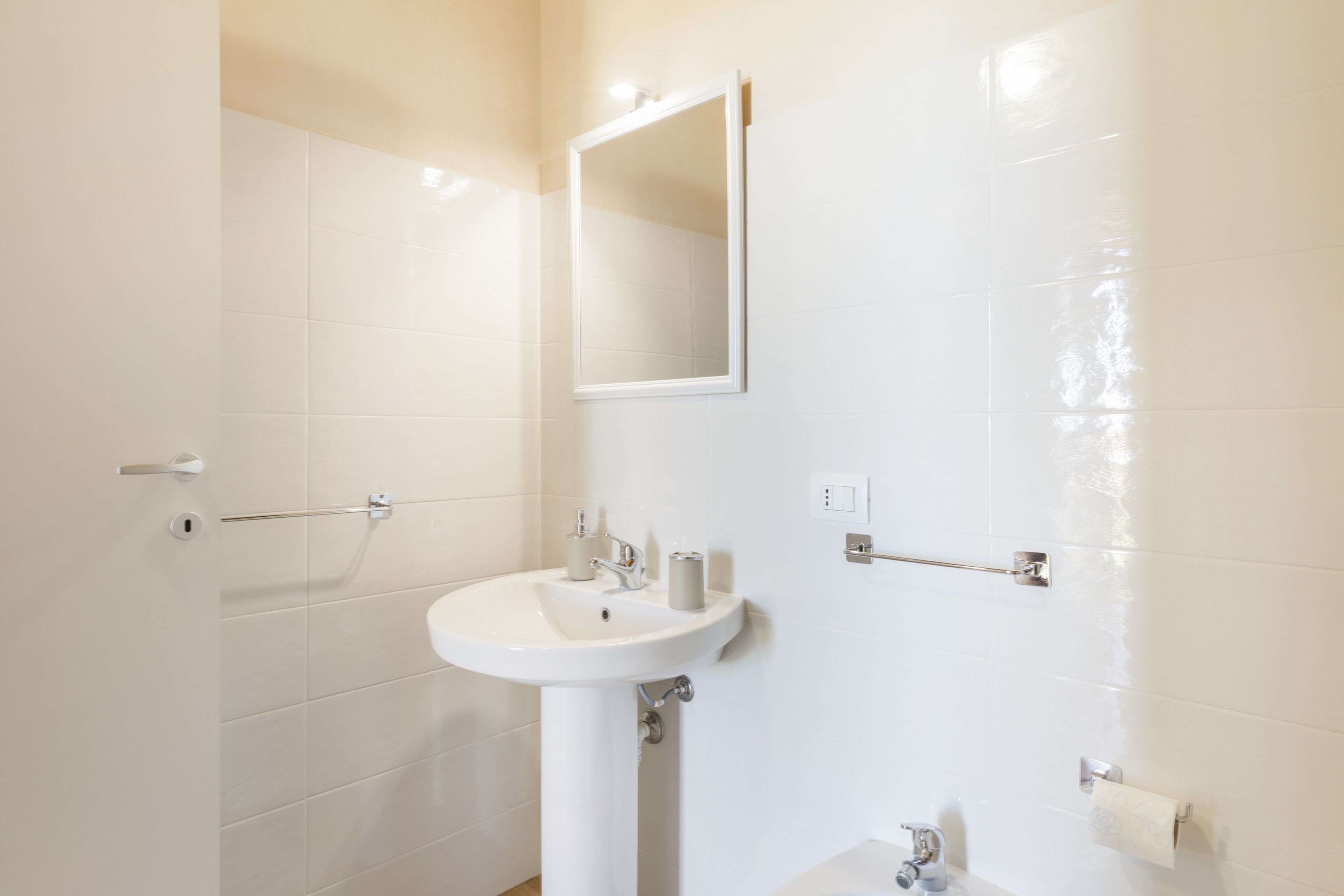 A bathroom with a white sink, mirror, and towel rack.