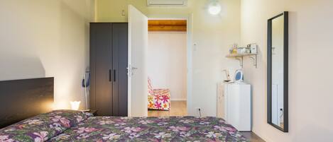 A bedroom with a bed, wardrobe, and a small kitchenette area.