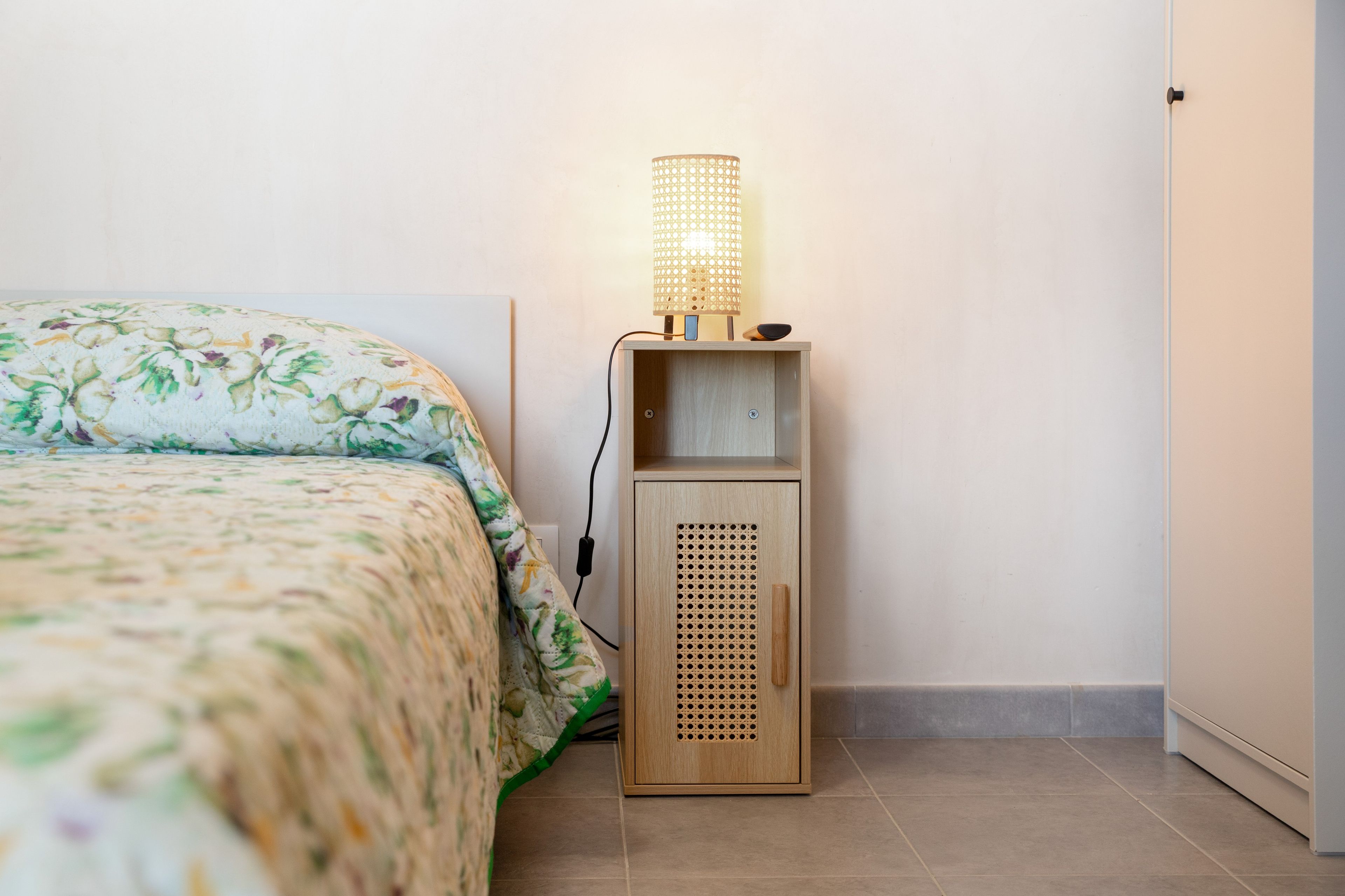 Un dormitorio con cama, una mesita de noche con lámpara y un armario de madera.