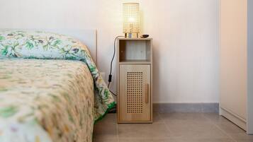 Un dormitorio con cama, una mesita de noche con lámpara y un armario de madera.