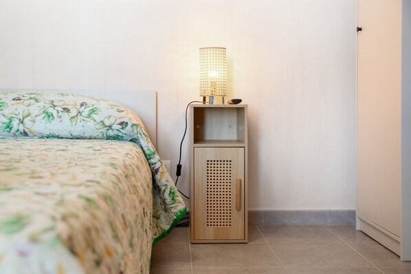 Un dormitorio con cama, una mesita de noche con lámpara y un armario de madera.