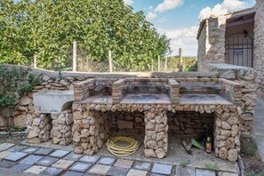 An outdoor grill area with stone walls and a poolside entrance. - Apartment 'N8' with Shared Pool, Balcony and Air Conditioning (Vittoria)