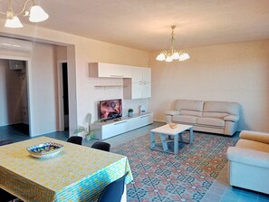 Ein modernes Wohnzimmer mit einer Couch, einem Esstisch und einem Fernseher.