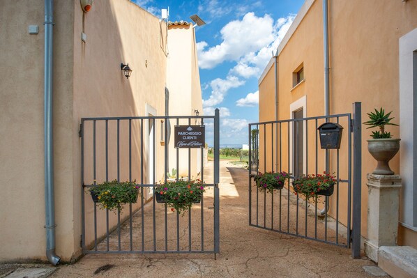 Une entrée fermée par un portail mène à un bâtiment sur lequel est apposée une pancarte indiquant un espace de stationnement réservé aux clients.
