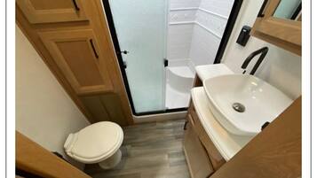 Een douche, handdoeken, zeep, toiletpapier