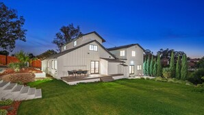 Une maison moderne à deux étages, dotée d’un patio couvert et d’une pelouse bien entretenue.