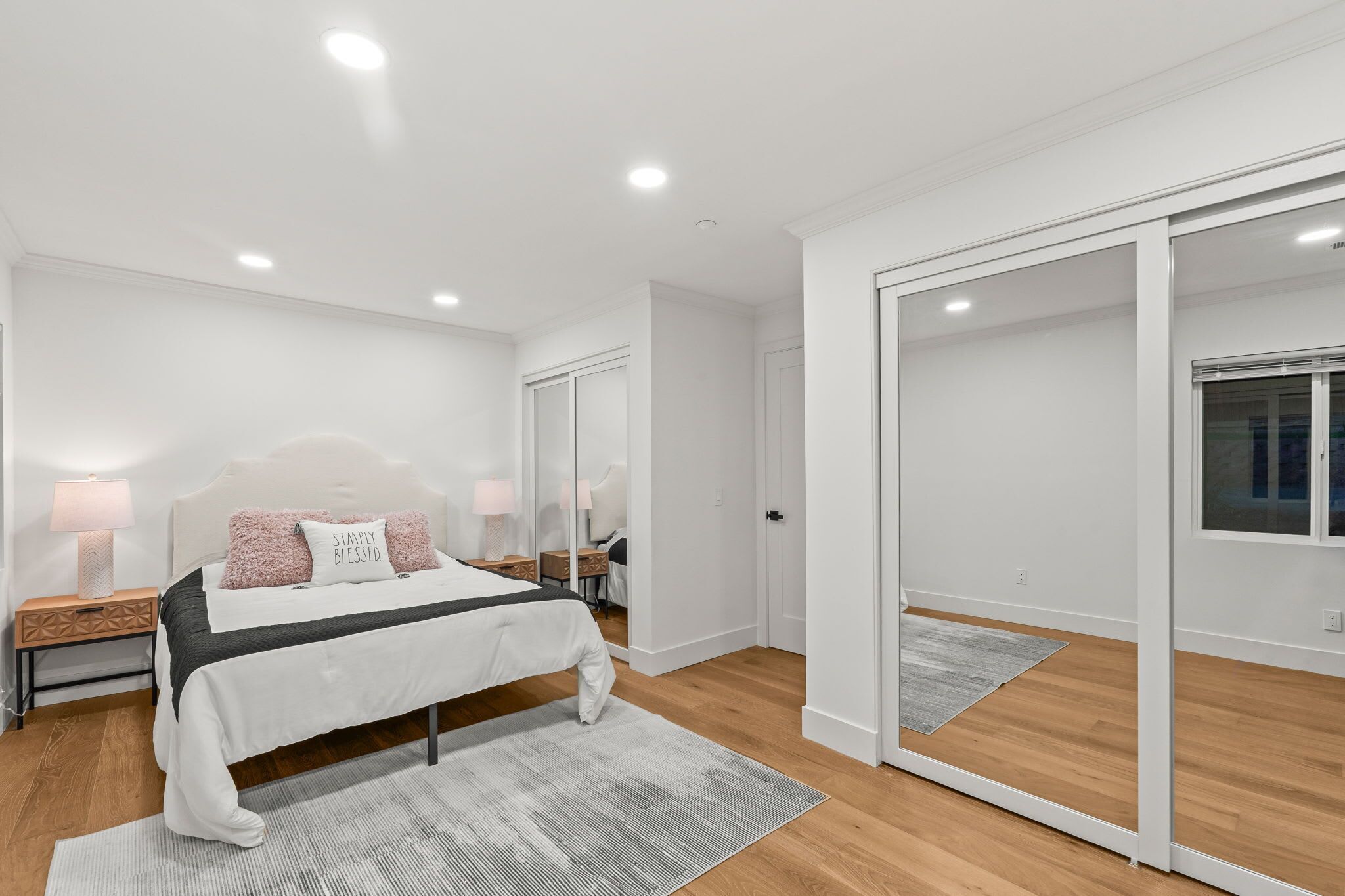 Une chambre à coucher moderne avec un lit, des tables de chevet, un miroir et un placard à portes coulissantes.