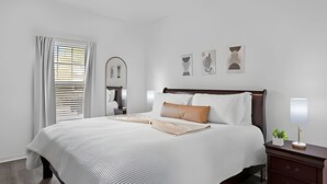 Una camera da letto ben ordinata con un letto grande, un comodino con una lampada e uno specchio a parete.