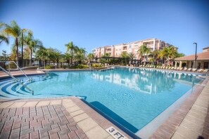 Una piscina amb un indicador de profunditat de 3 peus, envoltada de palmeres i un edifici amb balcons.