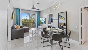 Ein modernes Wohnzimmer mit Sofa, Esstisch, Stühlen und Fernseher.