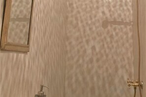 A bathroom with a textured wall, a mirror, and a shower area. - Riad with Swimming Pools (Marrakech)