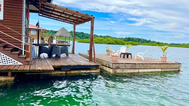 A wooden dock extending into a lake with a covered seating area and a small house. - Isla privada Mata Mua (Bocas del Toro)