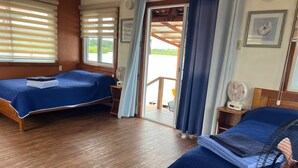 A room with two beds, wooden flooring, a fan, and a view through a door. - Isla privada Mata Mua (Bocas del Toro)