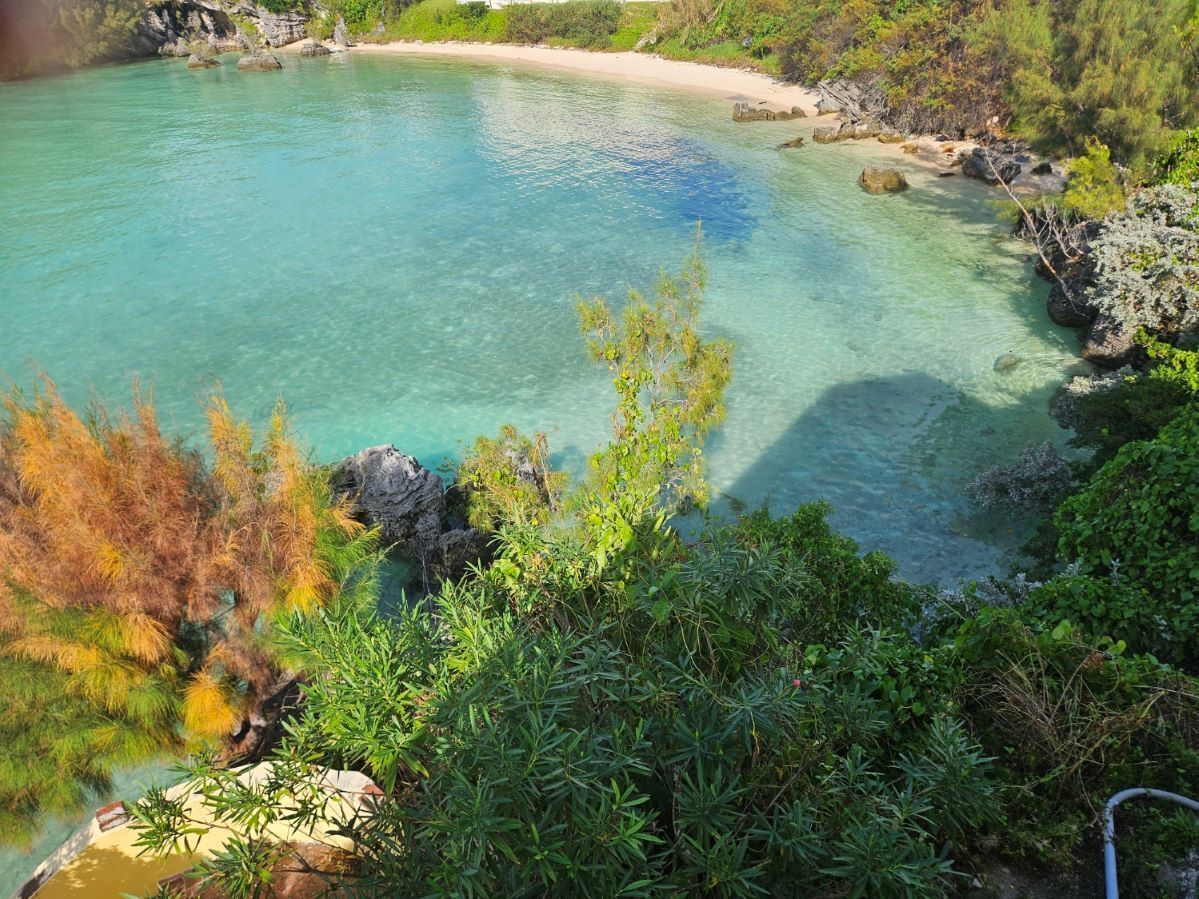 A coastal landscape with clear turquoise waters, rocky outcrops, and dense vegetation.