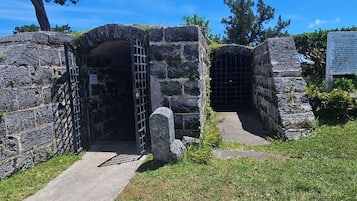 A stone structure with a metal gate, a paved entrance, and a grassy area.