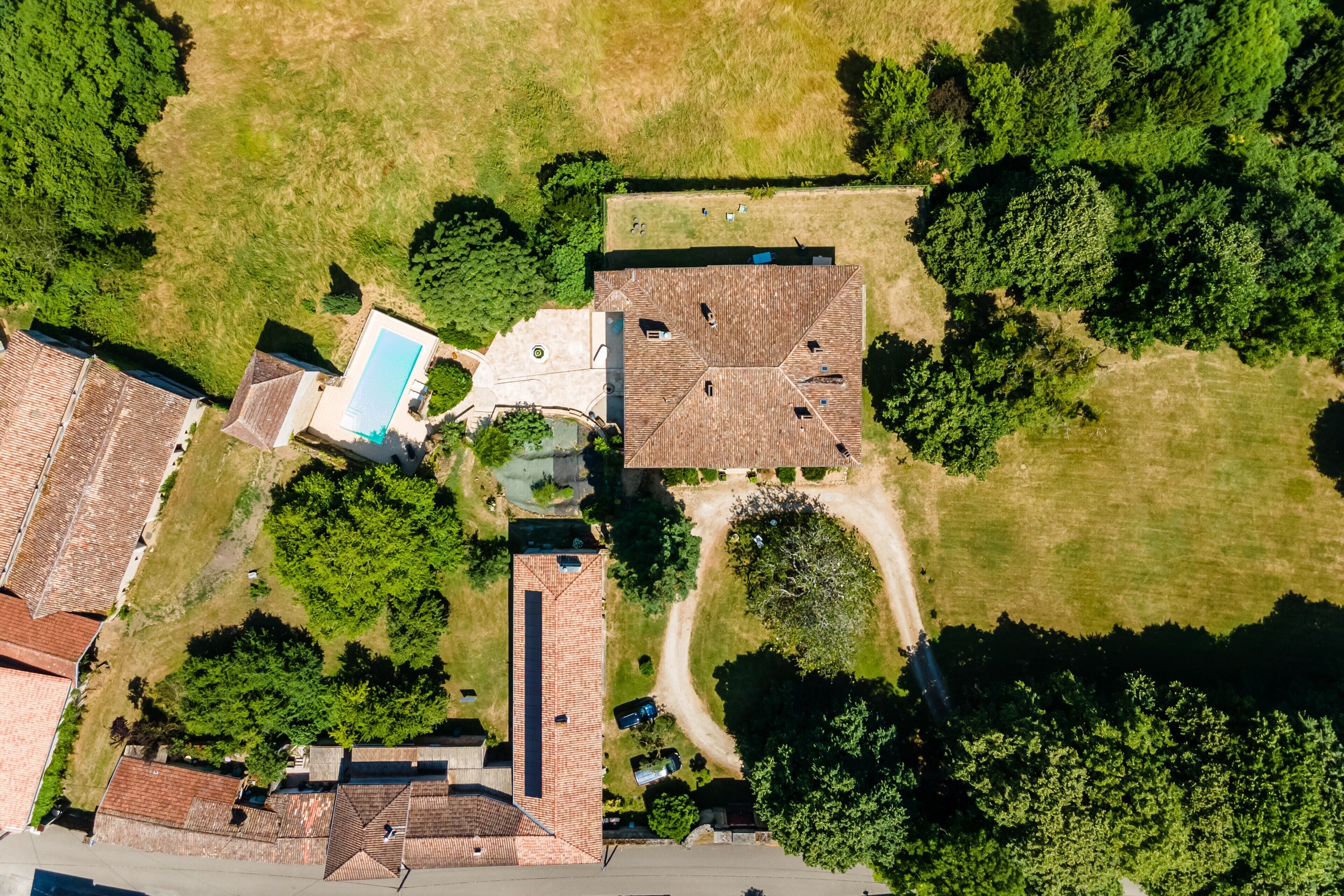 Eine Vogelperspektive auf eine Wohngegend mit mehreren Häusern, einem Swimmingpool und umliegender Bepflanzung.