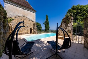 A swimming pool with lounge chairs, a stone building, and a clear blue sky. - Florence Room — Italian Elegance and Modern Comfort (Puybarban)