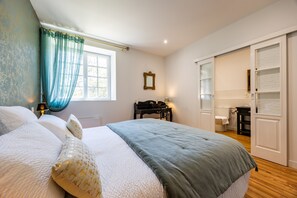 A bedroom with a bed, a desk, a chair, a wardrobe, and a window with curtains. - Florence Room — Italian Elegance and Modern Comfort (Puybarban)
