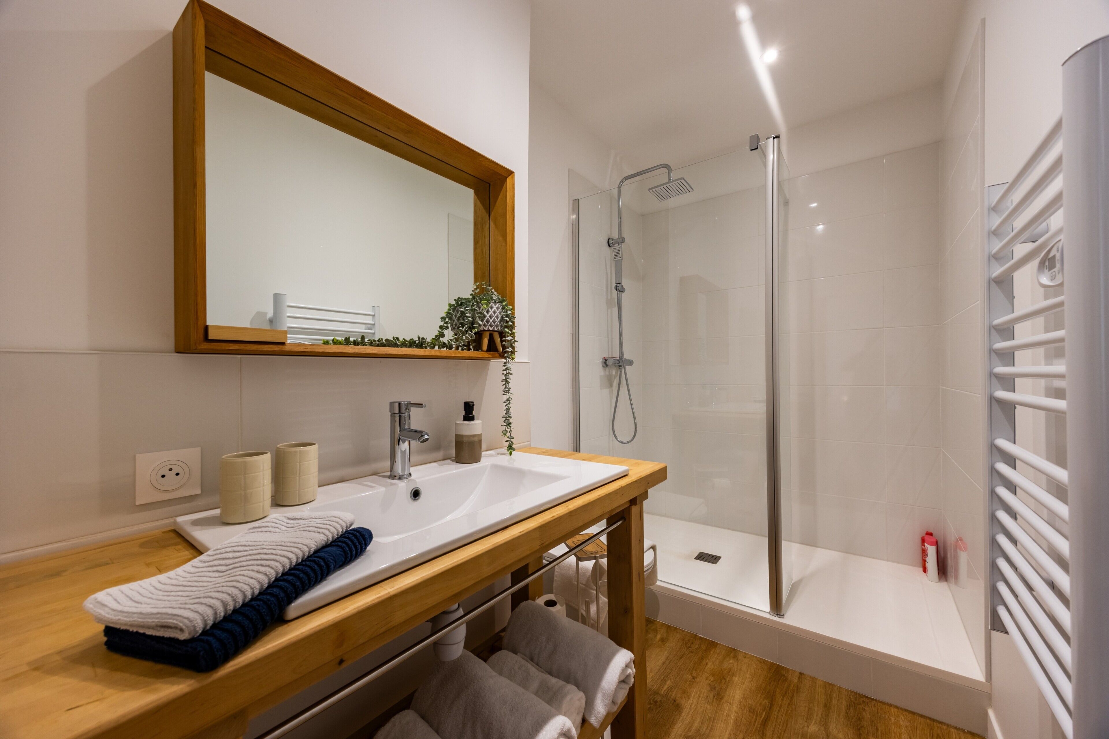 A modern bathroom with a wooden vanity, a large mirror, a sink, a shower, and a bathtub.