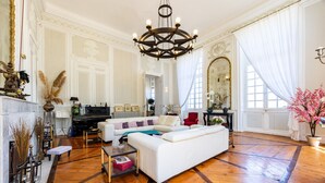 Ein großzügiges Wohnzimmer mit einem weißen Sofa, Holzböden, einer großen Chandelier und einem Kamin.