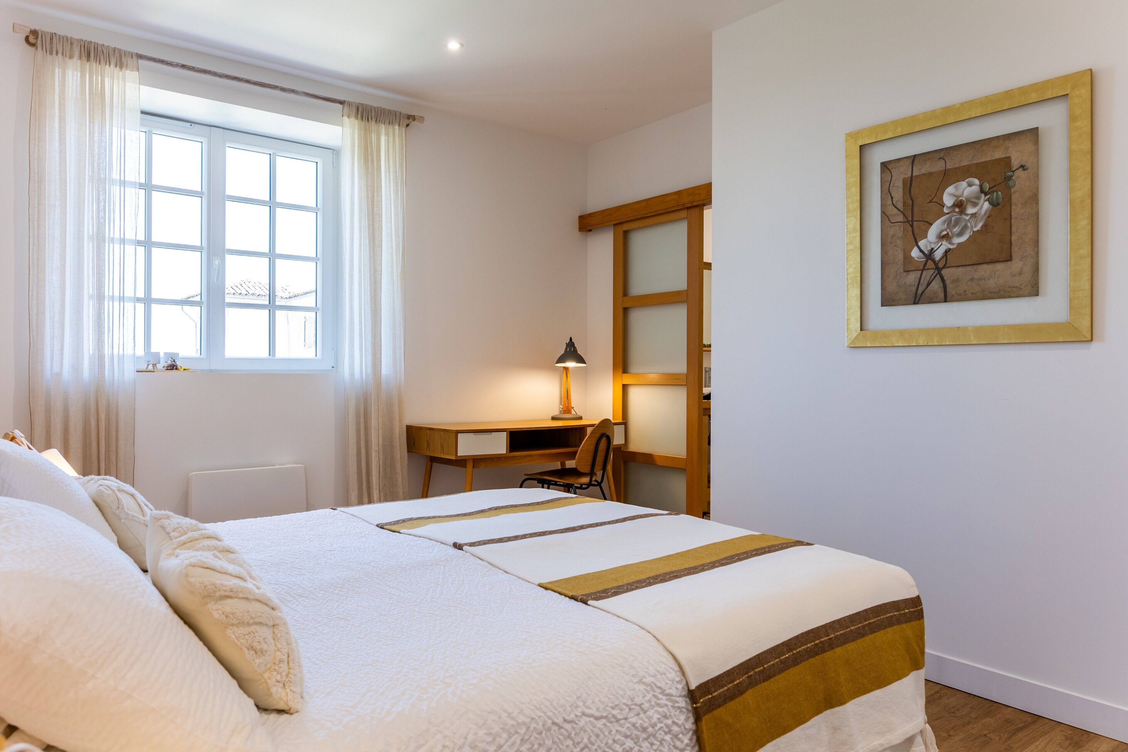 A bedroom with a bed, a desk, and a chair.