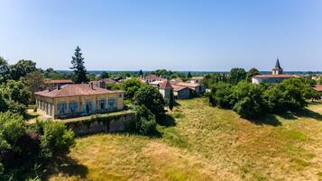 Un village rural avec des bâtiments traditionnels, une église et une grande maison dotée d’un jardin.