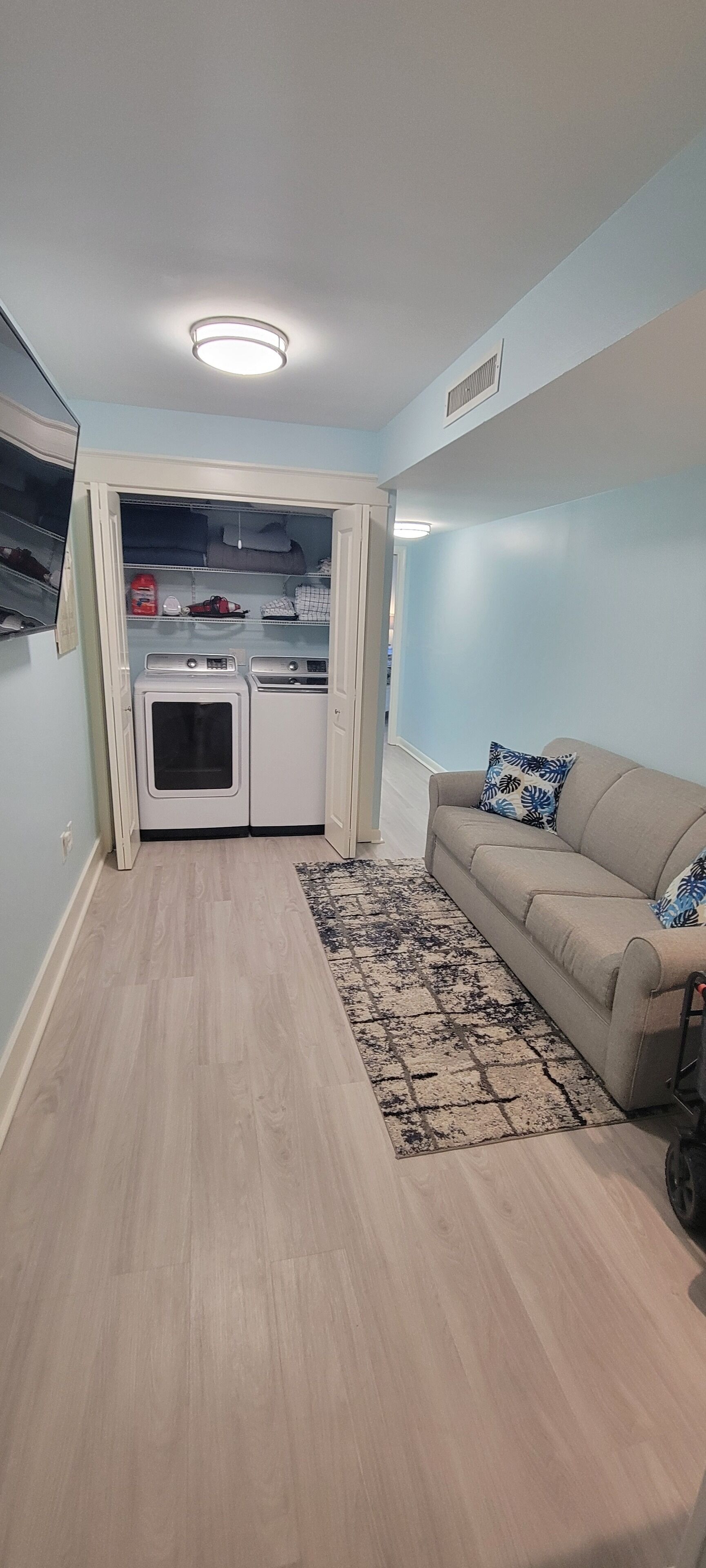 A compact living space with a kitchenette, a beige sofa, and a patterned rug.