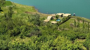 A lake surrounded by hills with a small dock and a hut. - Dar diafa Jennane (Zoumi)