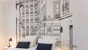 Een slaapkamer met een bed, twee kussens, een nachtkastje met een lamp en een muurschildering van gebouwen.