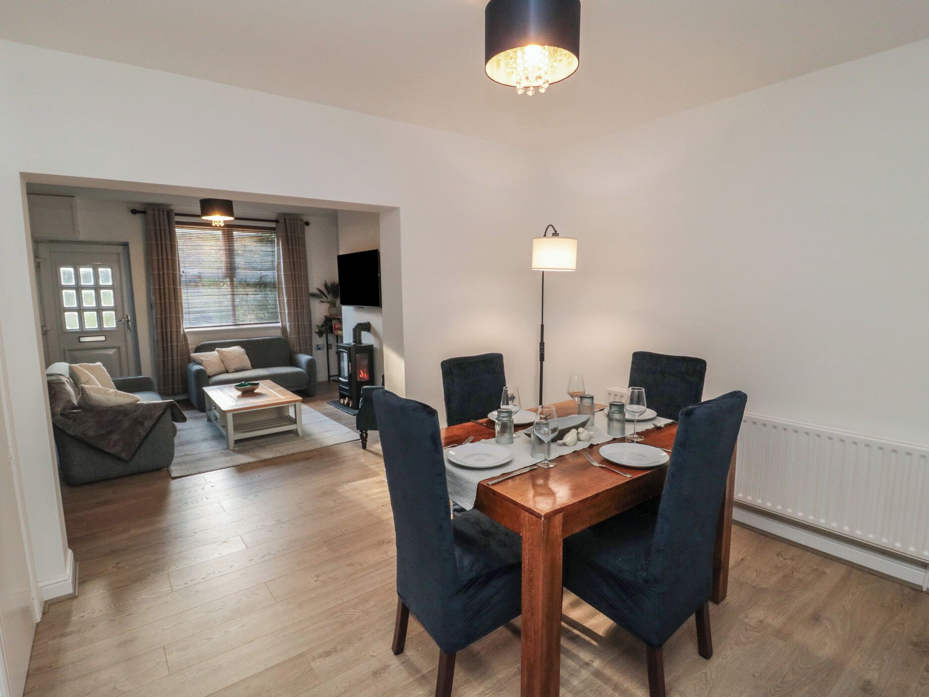 A modern living room with a dining area, wooden flooring, and a fireplace.