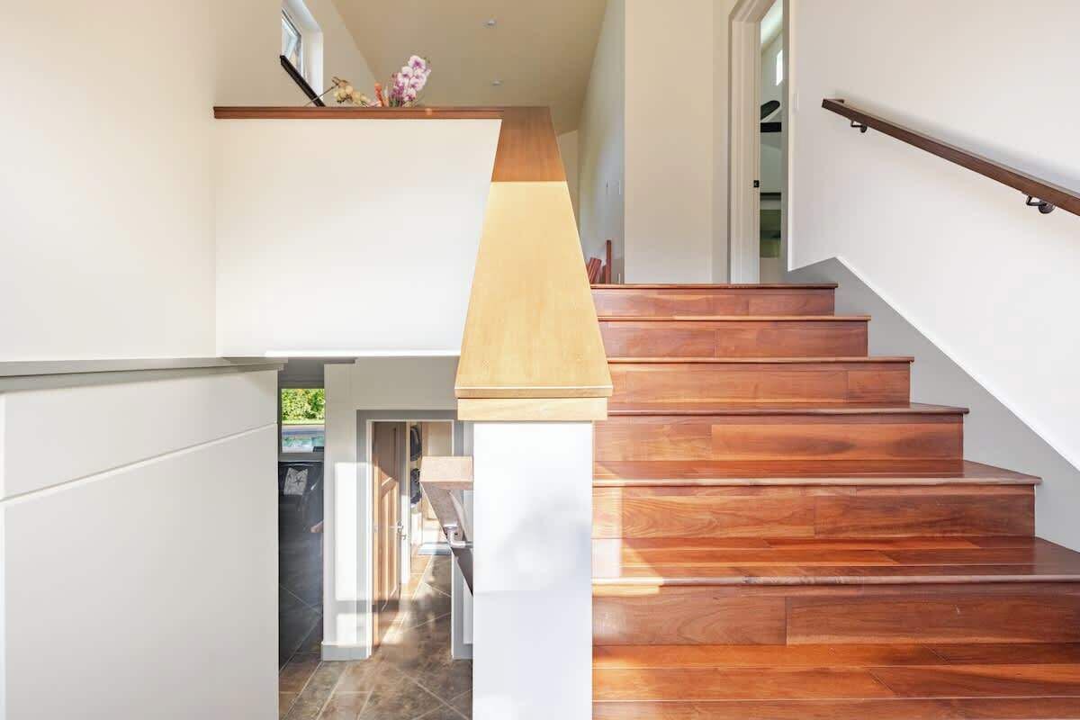 Una escalera moderna con escalones de madera y un pilar blanco.