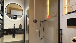 Une salle de bain moderne avec une douche à parois de verre, des toilettes noires et un meuble-lavabo avec un miroir.