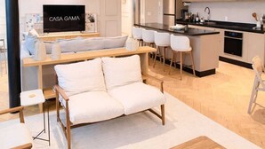 Moderni olohuone, jossa on sohva, sohvapöytä ja televisio, jonka näytöllä näkyy teksti ’CASA GAMA’.