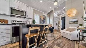 Una cocina moderna con armarios blancos, electrodomésticos de acero inoxidable y una isla de madera con taburetes de bar.