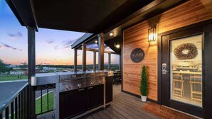 Un espacio al aire libre cubierto con una parrilla, una terraza de madera, una planta en maceta y una puerta con un letrero que dice "NUMB".