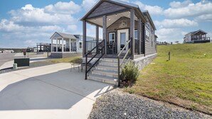A building with a covered porch, a staircase, and a small outdoor seating area. - The Grape Escape (Fredericksburg)