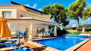 A poolside area with lounge chairs, a table with drinks, and a covered seating area. - Casa Luna with Saltwater Pool – Private Pool, Garden & Parking (Olhos de Água)