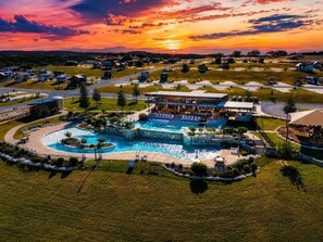 A resort with a large pool, a covered area, and a view of the sunset. - My Songbird |Firepit & Sunset Views! (Fredericksburg)
