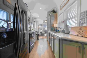 A modern kitchen with stainless steel appliances, a wooden countertop, and a view of the living area. - KICKIN'BACH (Fredericksburg)