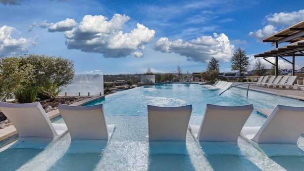 A swimming pool with lounge chairs and a view of the ocean. - Little Blue Haus with Hot Tub! (Fredericksburg)