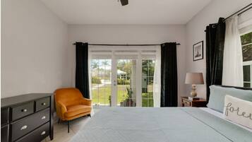 Un dormitorio con cama, mesita de noche, lámpara, silla y cómoda.