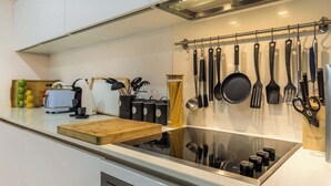 Una cocina moderna con estufa integrada, tabla de cortar de madera y varios utensilios colgados en la pared.